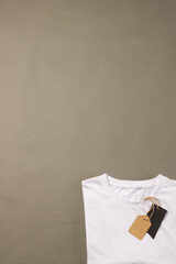 A white t-shirt with a blank tag lies on a plain background, with copy space