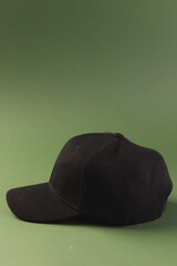 A black baseball cap is displayed against a green background, with copy space