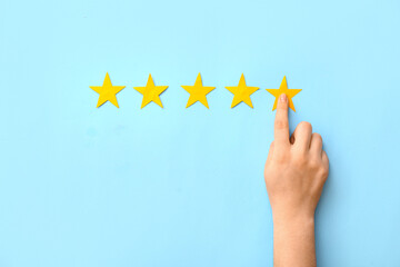 Female hand and five stars rating on blue background. Customer experience concept
