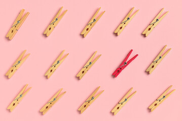 One pink clothespin among wooden ones on color background. Concept of uniqueness