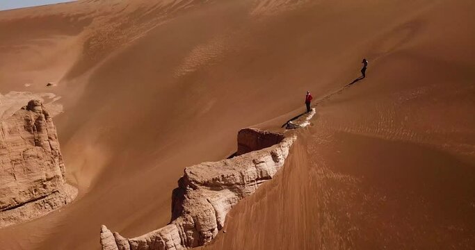 fly over a big rock cliff surrounded by desert sand dune in lut geopark natural heritage in UNESCO world list adventure hiking in dry climate golden hills in Iran scenic Arabian natural landscape