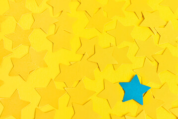 One blue star among yellow ones on color background. Concept of uniqueness