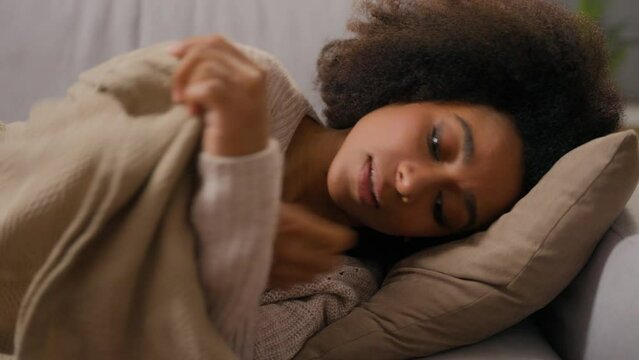 Close-up of young African American woman relaxing sleeping daytime covered with blanket lying on pillow couch in living room cute girl ethnic female peaceful rest sleep nap on comfortable sofa at home