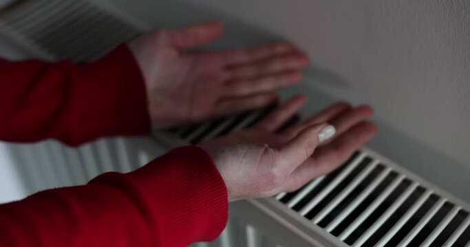 Central heating system at home and women's hands on radiator