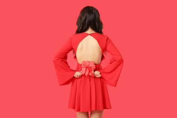 Beautiful young Asian woman with gift box on red background, back view. Valentine's Day celebration