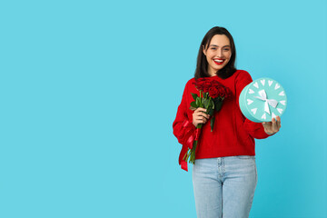 Beautiful young happy woman with gift box and bouquet of roses on blue background. Valentine's Day...