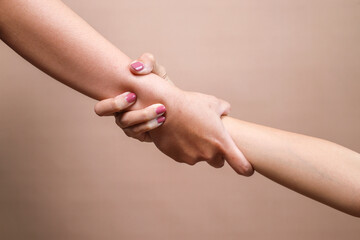 Hands hold each other for salvation over beige background.