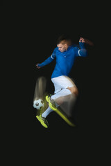 Sporty young man playing with soccer ball in motion on black background