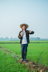 Asian female farmer dressed in brown blouses, jeans Stand and pose holding banknote money with a smiling expression.