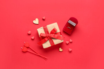 Composition with engagement ring, gift box and decor for Valentine's Day celebration on red...