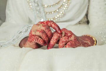 Henna on the hands of a bride in a wedding dress.