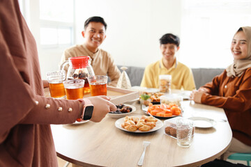Muslim woman serving glasses of tea on wooden tray for friends during breakfasting in Ramadan