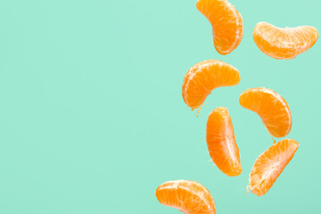 Flying pieces of sweet peeled mandarin on turquoise background