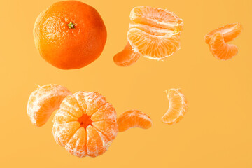 Flying sweet ripe mandarins on yellow background