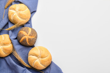 Napkin with delicious kaiser rolls and wheat ears on white background - obrazy, fototapety, plakaty