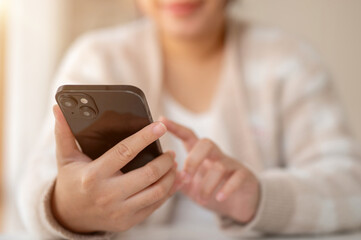 A woman using her smartphone while sitting at a table by the window in a coffee shop.