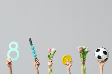 Female hands with paper figure 8, sports equipment and beautiful tulip flowers for International Women's Day on grey background