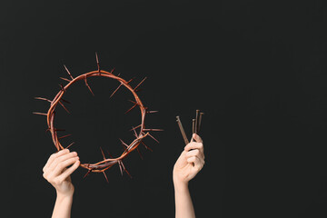 Female hands with crown of thorns and nails on dark background. Good Friday concept