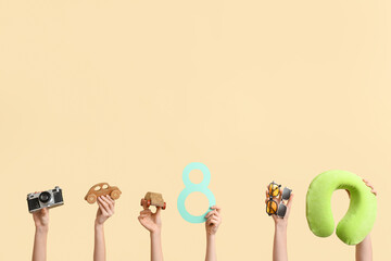 Female hands with paper figure 8, travel pillow, wooden cars and sunglasses on color background. International Women's Day