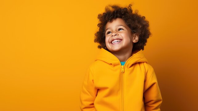 A cute little boy, smiling, stands on a yellow background. A happy child, the concept of joy, surprise.