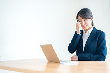 仕事中に目を擦るスーツを着た日本人女性