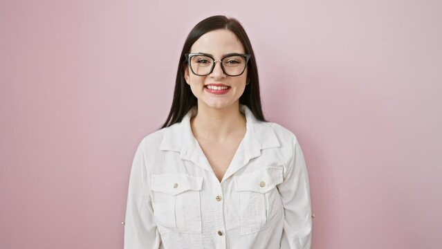 Confident young hispanic woman enjoying her lucky day, smiling proudly with a cool, natural, beautiful glow on her face. standing over an isolated pink background, radiating positive vibes