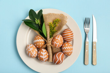 Beautiful table setting with Easter eggs and yellow flowers on blue background