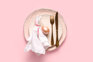 Beautiful table setting with Easter egg and gypsophila flowers on pink background