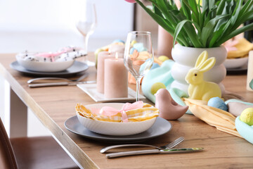 Beautiful Easter table setting with bunny, cutlery and painted eggs