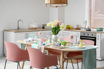 Modern interior of stylish kitchen with Easter table setting, counters and vase of flowers