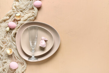 Table setting for Easter celebration with painted eggs and cloth on beige background. Top view
