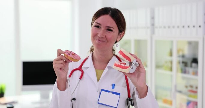 Plastic jaws and a sweet pink donut in hands of dentist
