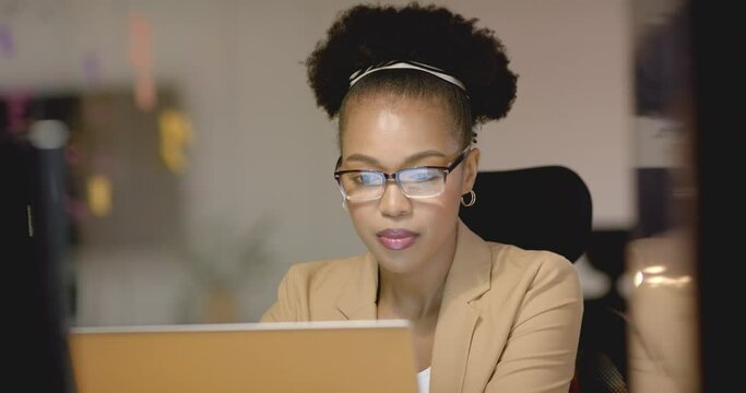 Focused young African American woman works diligently on her business laptop in an office setting