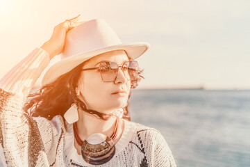 Portrait of a curly haired woman in a white hat and glasses on the background of the sea.
