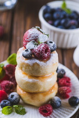 Cheesecakes served with berries and condensed milk