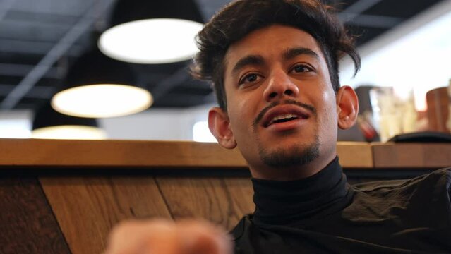 Sri Lankan man sitting in cafe and chit chatting with his friends, portrait view