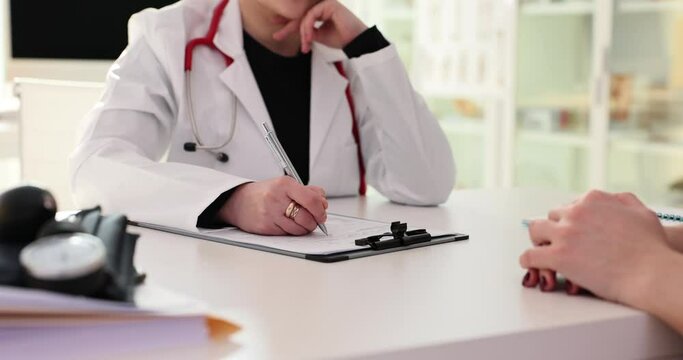 Female doctor and patient writing and discussing diagnosis