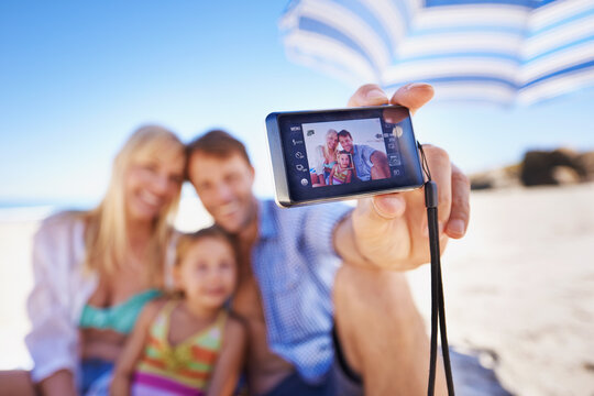 Happy family, beach and selfie with camera for photography, picture or moment in outdoor nature. Mother, father and child with smile for photo, capture or bonding memory together on the ocean coast