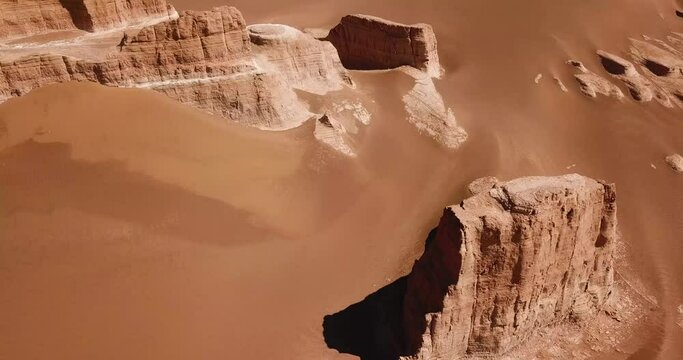 Pillar stone rock cliff surrounded by smooth wonderful sand dune in a hot summer season in mountain desert climate Yazd lut desert in Iran wonderful formation natural scenic heritage in middle east