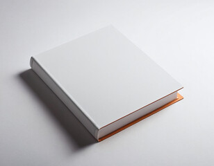 A closed white hardcover book with a hint of orange, resting on a white surface.