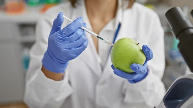 Scientist in lab coat injecting green apple with syringe, concept of genetic modification
