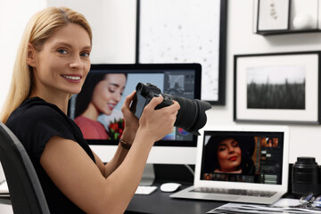 Naklejka premium Professional photographer with digital camera at table in office