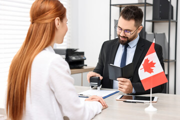 Immigration to Canada. Smiling embassy worker approving woman's visa application form in office - obrazy, fototapety, plakaty