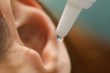 Woman applying medical ear drops, macro view