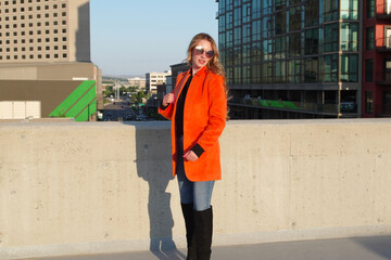 Stunning Blue-Eyed Model in Orange Jacket, Posing atop City Rooftop