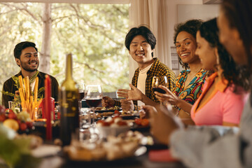 Group of happy young friends is drinking wine while having holiday dinner home party together