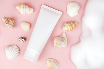 cosmetic moisturizer cream tube bottle, soap foam, bubbles, seashells on pink background. bath...