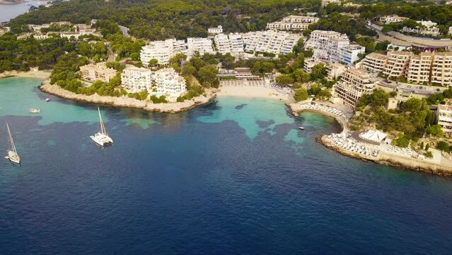 Playa illetas with turquoise water, yachts, and resorts under sunny skies, aerial view