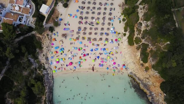 Retreating overhead drone shot of the beachfront of Cala Anguila, a cove located in the island of Mallorca off the coast of Spain in the Mediterranean Sea.