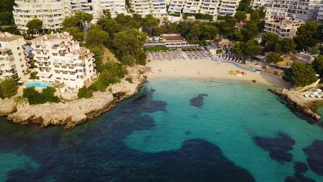 Playa illetas with clear turquoise waters and sunbathers on the beach, mallorca, spain, aerial view